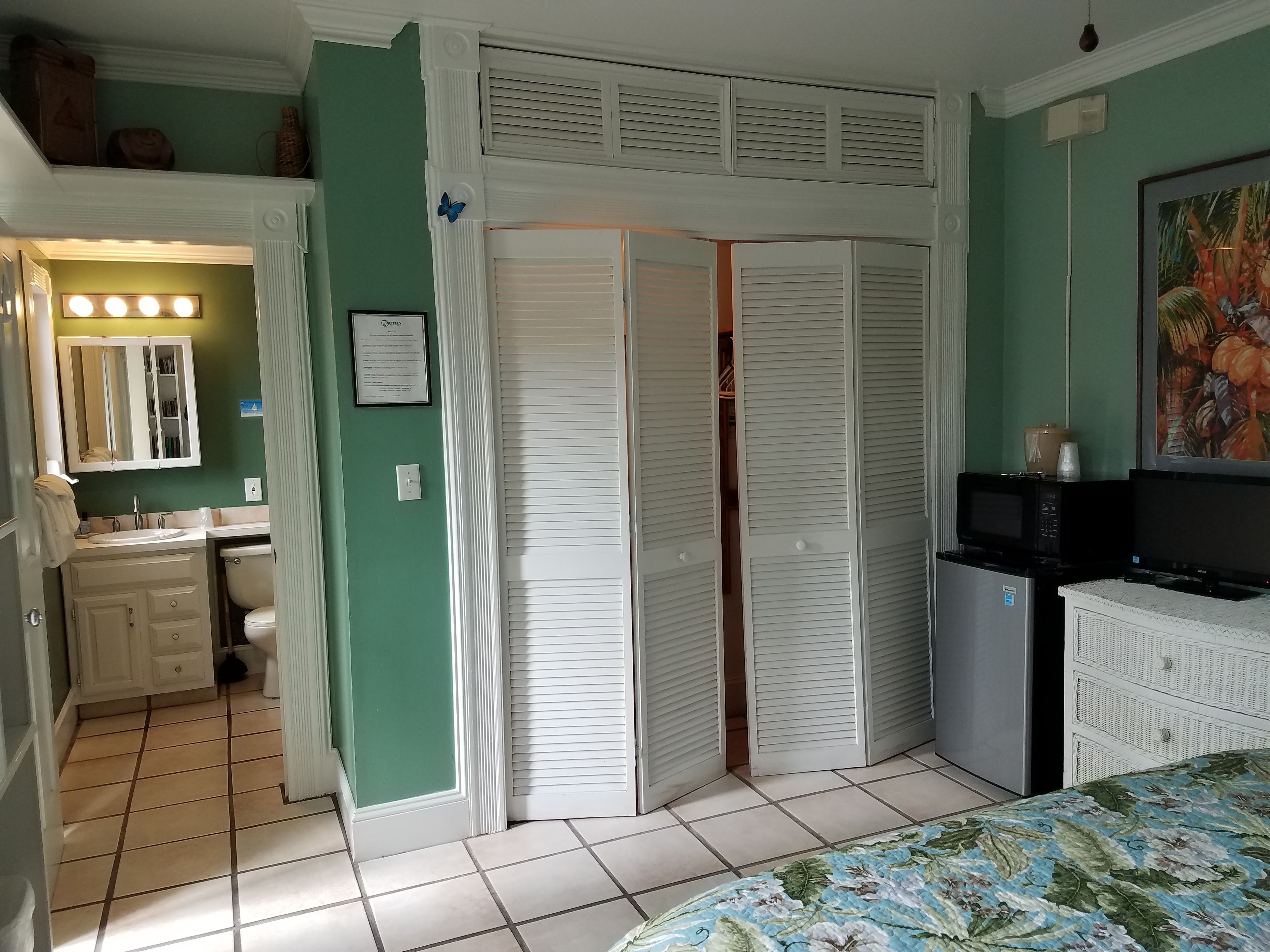 Un dormitorio con cama, televisor, microondas y refrigerador.