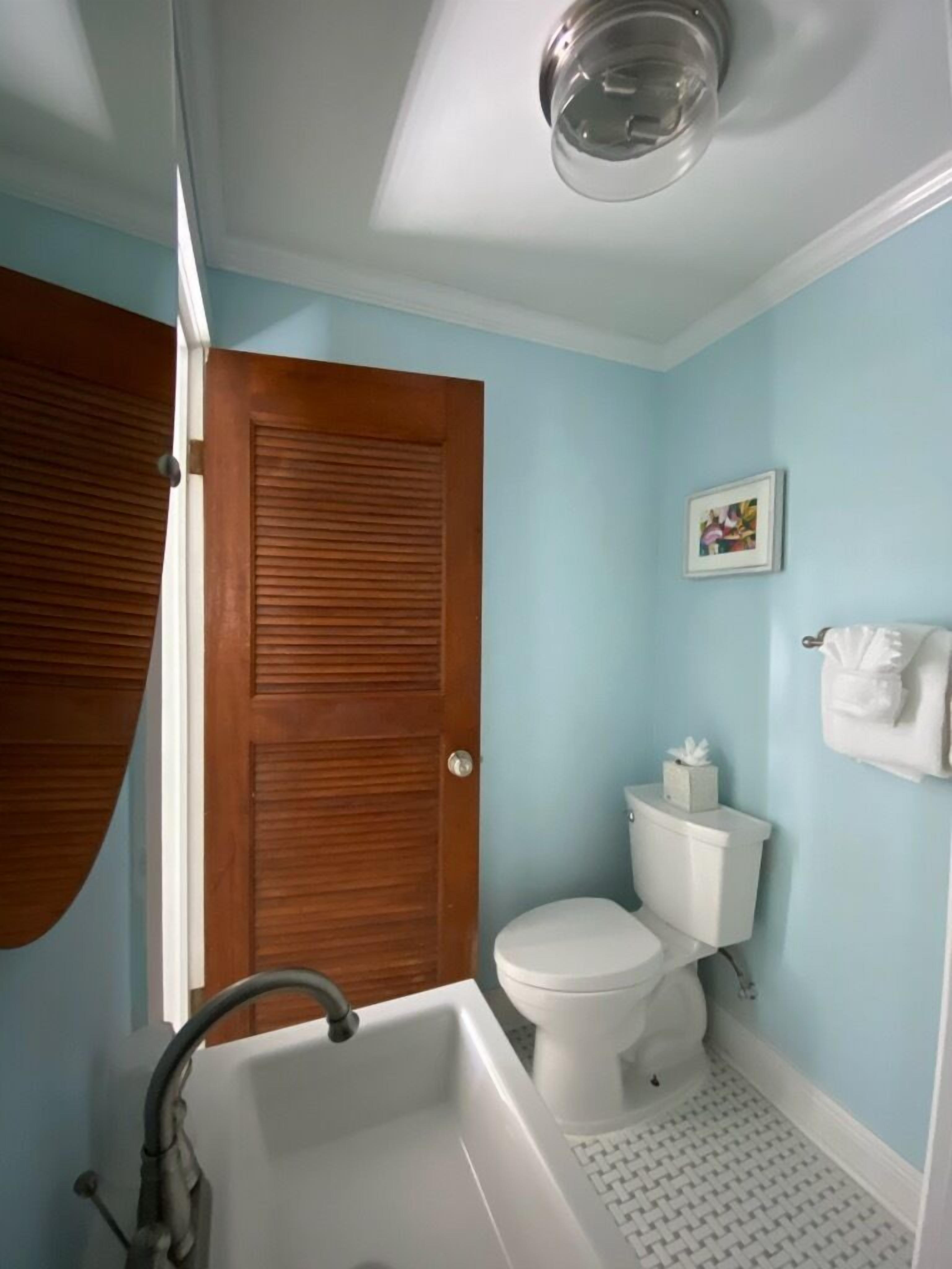 Een badkamer met een houten deur, een wit toilet en een bad.