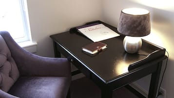 A dark wooden desk with a lamp, a notebook, and a book titled "Natalies".