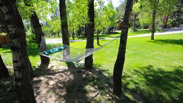 A hammock between trees in a grassy area.