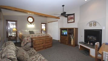 A bedroom with a bed, a wooden bench, a fireplace, and a ceiling fan.