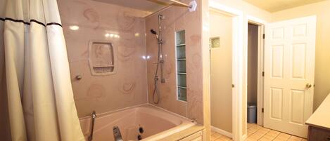 A bathroom with a bathtub, shower, and a toilet.