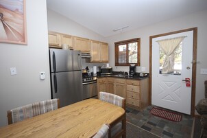 Una cucina compatta con mobili in legno, un frigorifero in acciaio inossidabile e un tavolo con sedie.