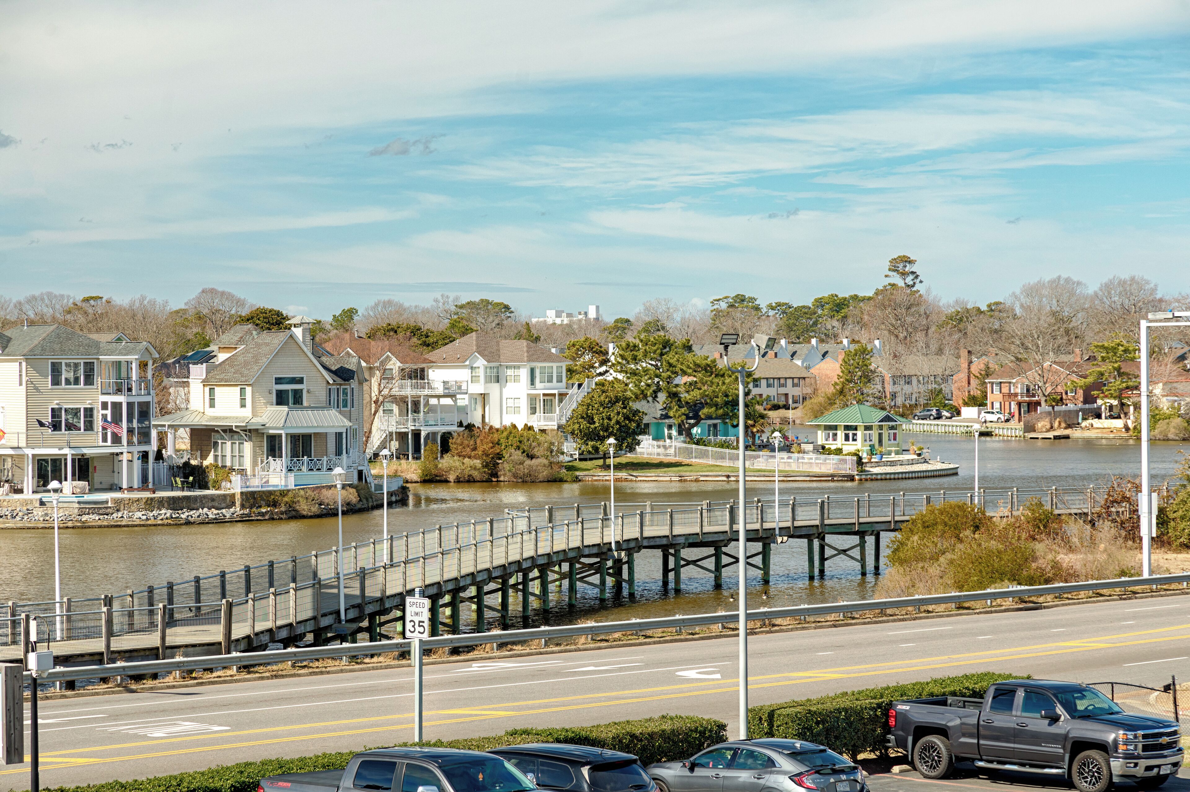 A waterfront view with a pedestrian bridge, houses, and a speed limit sign of 35.