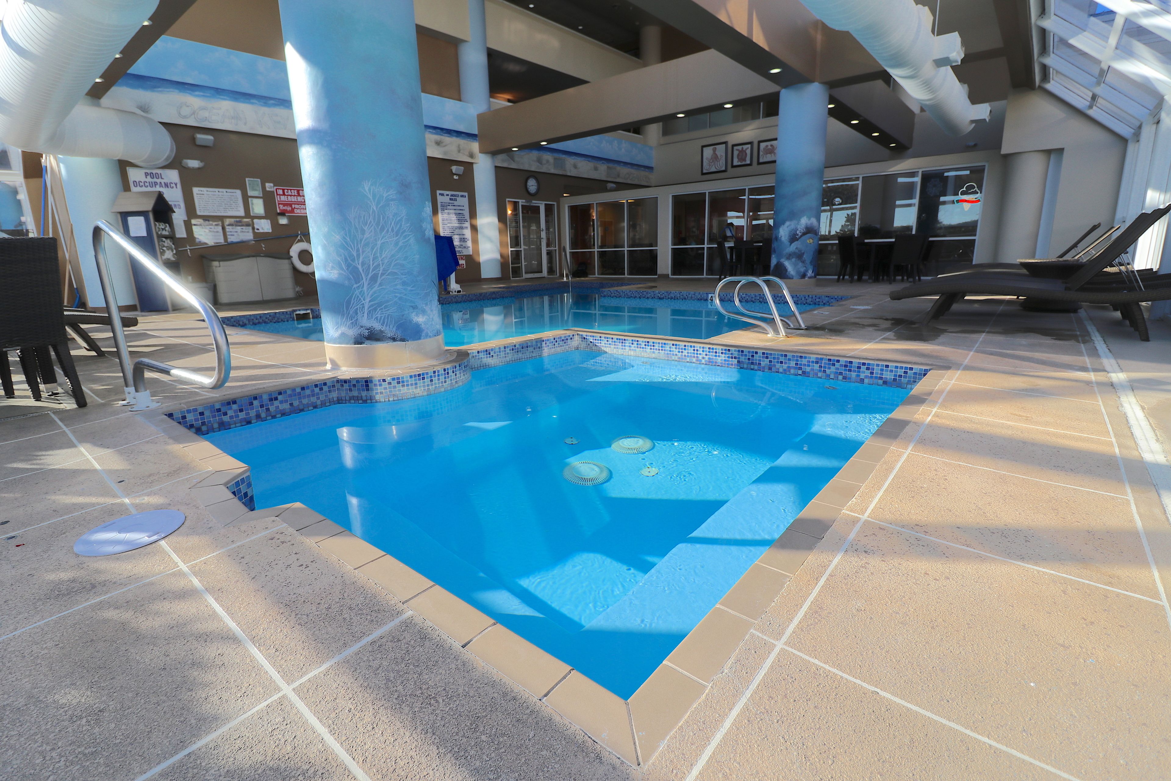 Area piscina interna con confini ben definiti, una sedia per il bagnino e una zona relax a bordo piscina.