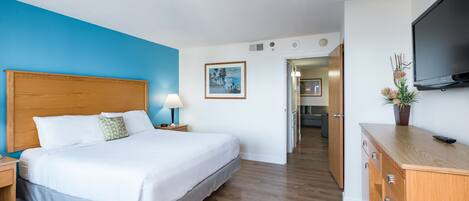 Habitación de hotel con una cama grande, cabecero de madera, mesita de noche con lámpara, televisor de pantalla plana en la pared y cómoda de madera.