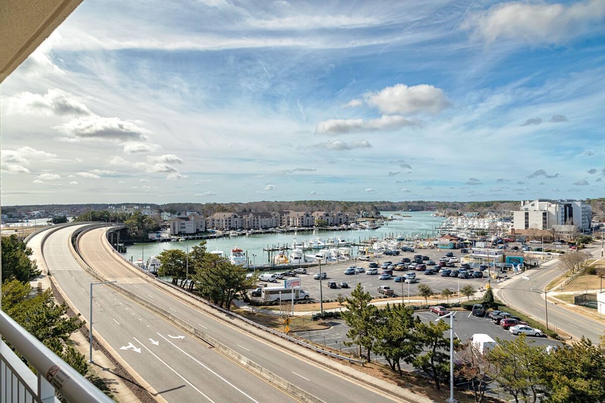 A marina with boats, a parking lot, and buildings in the background.