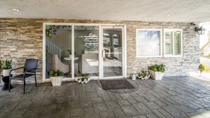 A covered outdoor area with stone walls, a glass door entrance, and outdoor seating.
