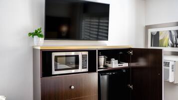Een moderne keuken met een ingebouwde magnetron, een vaatwasser en een flatscreen televisie die boven de aanrecht is bevestigd.