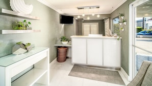 A modern bathroom with a glass vanity, a sink, a mirror, and a television mounted on the wall.