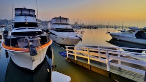 A marina with several boats docked, a wooden deck, and a white railing.