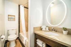 Een badkamer met toilet, douche, wastafel en spiegel.