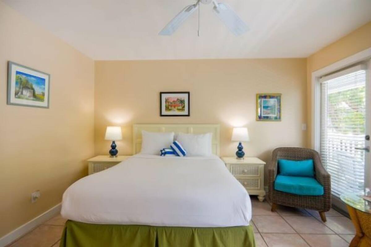 A bedroom with a bed, two bedside tables with lamps, a chair, and a ceiling fan.