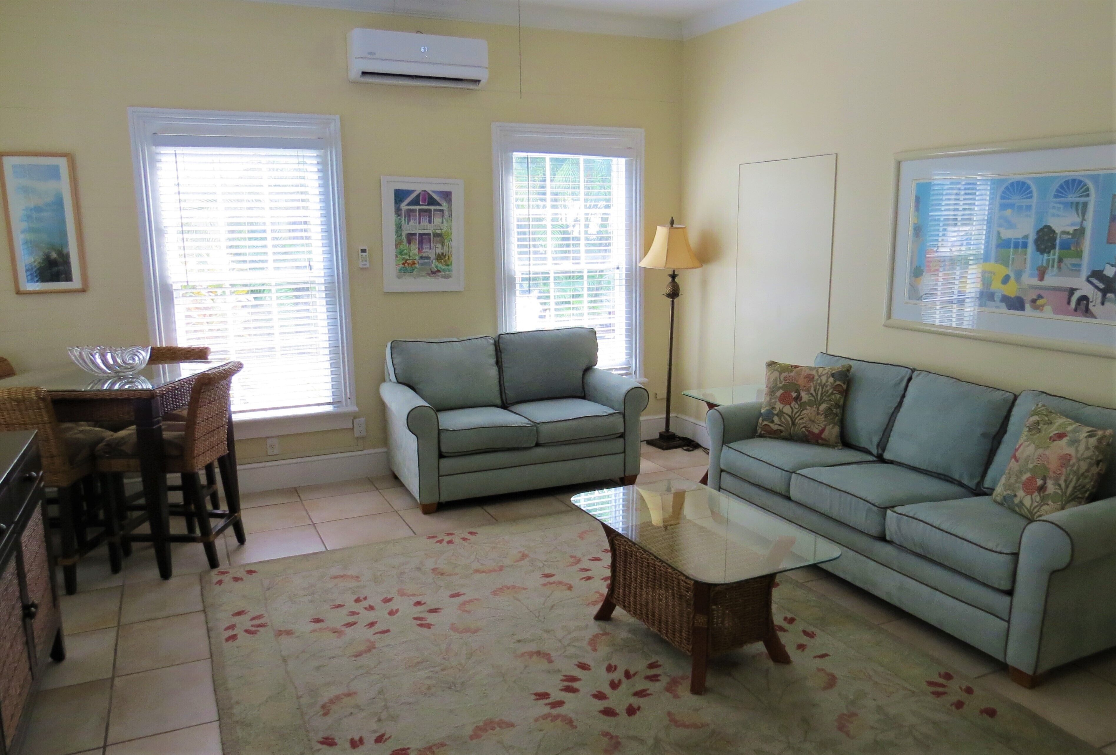 A living room with a sofa, a coffee table, and a dining area with chairs and a table.