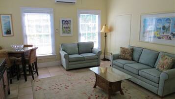 A living room with a sofa, a coffee table, and a dining area with chairs and a table.