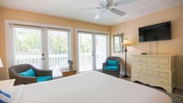 A hotel room with a large bed, a ceiling fan, a TV, a dresser, and a chair.
