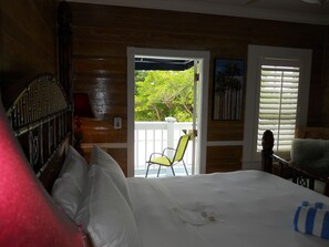 A room with a bed, a chair, and a view of greenery outside.