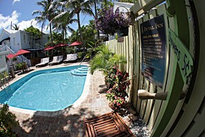 A pool area with lounge chairs, a wooden deck, and a sign detailing pool/spa rules.
