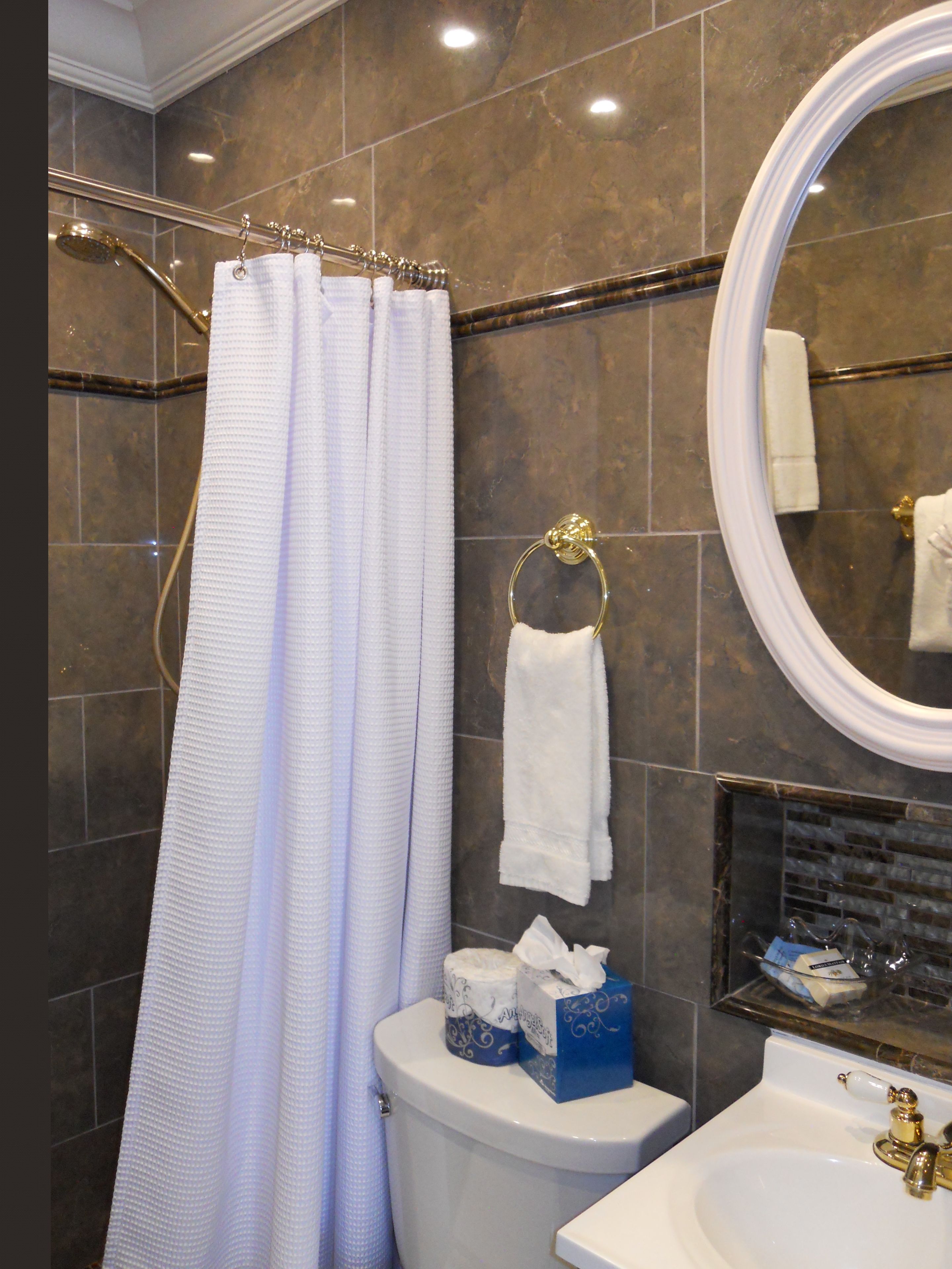 A bathroom with a shower curtain, a toilet, a sink, and a mirror.