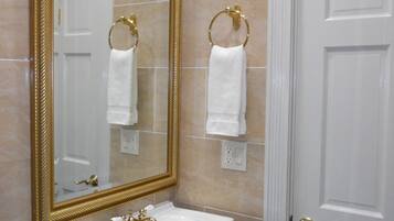 A bathroom with a large mirror, a sink, and two towel rings.