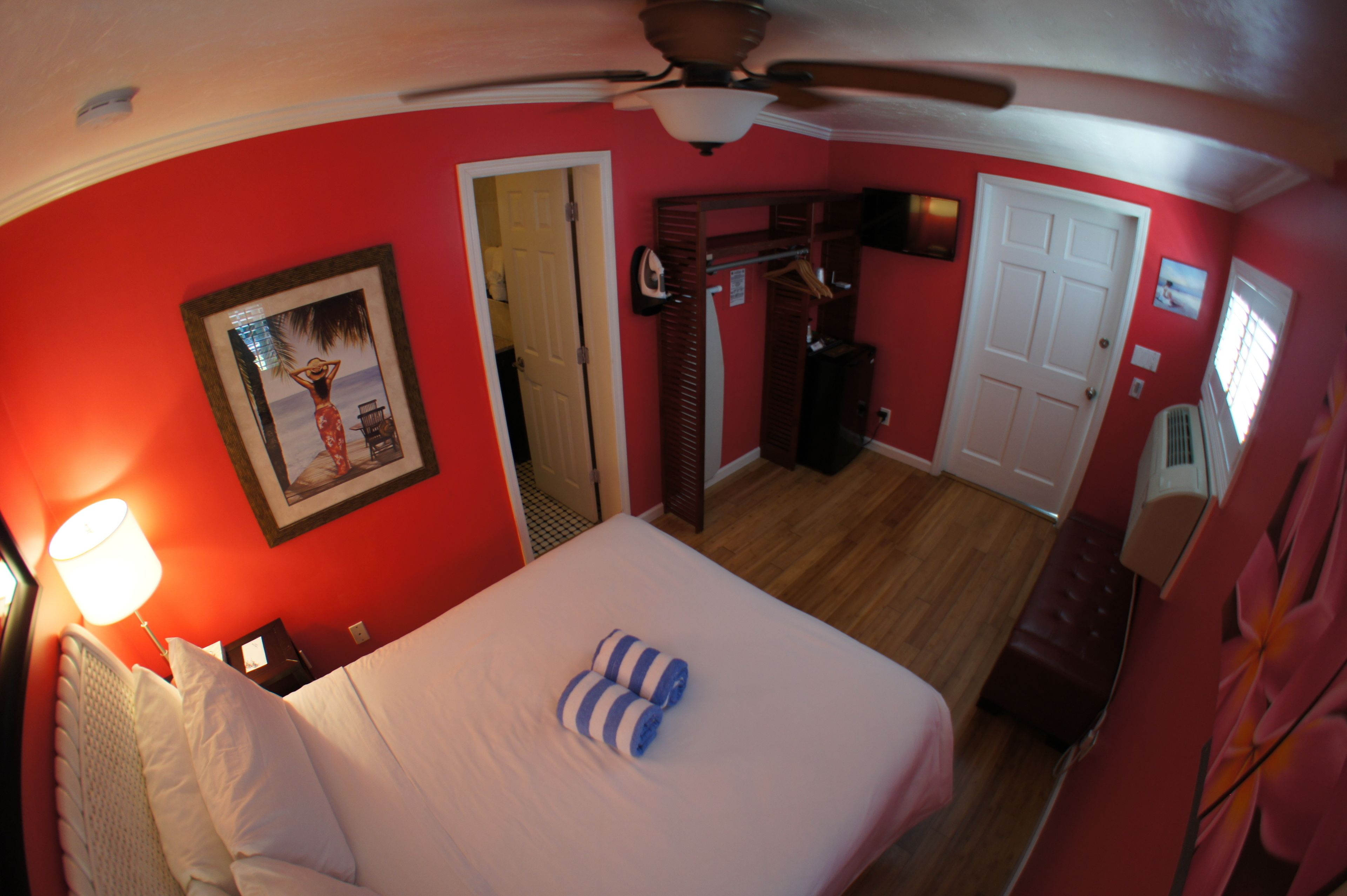 Une chambre d’hôtel équipée d’un lit, d’un ventilateur de plafond, d’une porte et d’un radiateur fixé au mur.