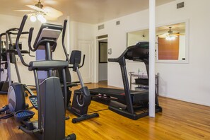 Kotikuntosali, jossa on kuntoilulaitteita, juoksumatto ja crosstrainer.
