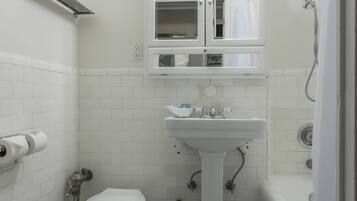 A small, white bathroom with a toilet, sink, and shower.
