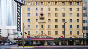 Un hotel con entrada principal, varios balcones y banderas.