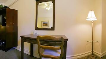A room with a wooden desk, a chair, a mirror, a lamp, and a cabinet.