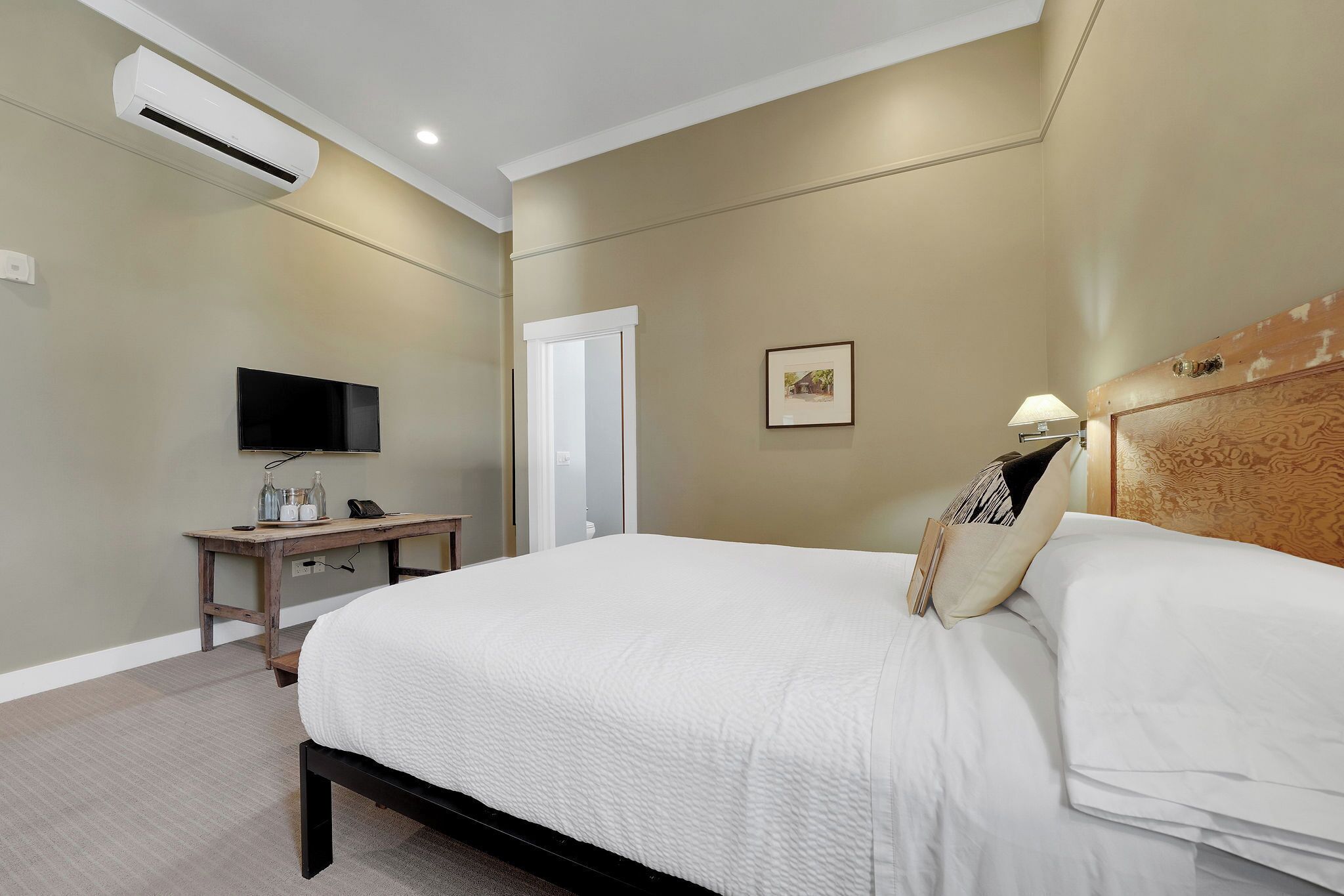 Habitación de hotel con cama, mesita de noche, televisor y equipo de aire acondicionado.