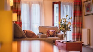 Ett vardagsrum med en soffa, ett soffbord och en vas med blommor.