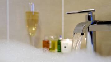 A bathroom with a running faucet, a glass of liquid, and toiletries on the counter.