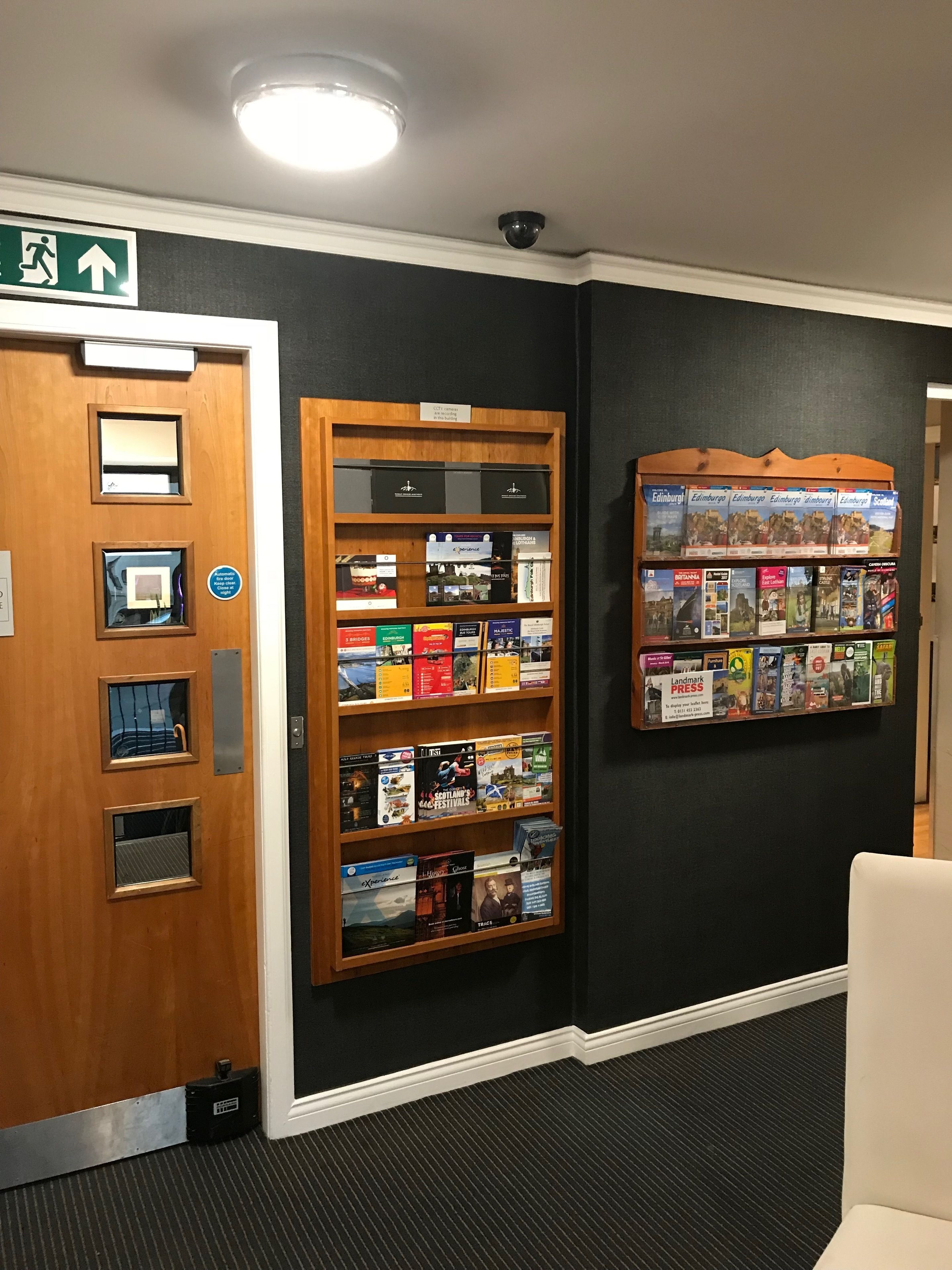 A reception area with a wooden bookshelf displaying various travel books and a wall-mounted display of travel guides.