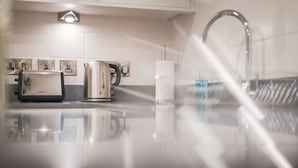 Ett modernt kök med en bänkskiva i rostfritt stål, en vattenkokare, en brödrost och en pappershandduksdispenser.