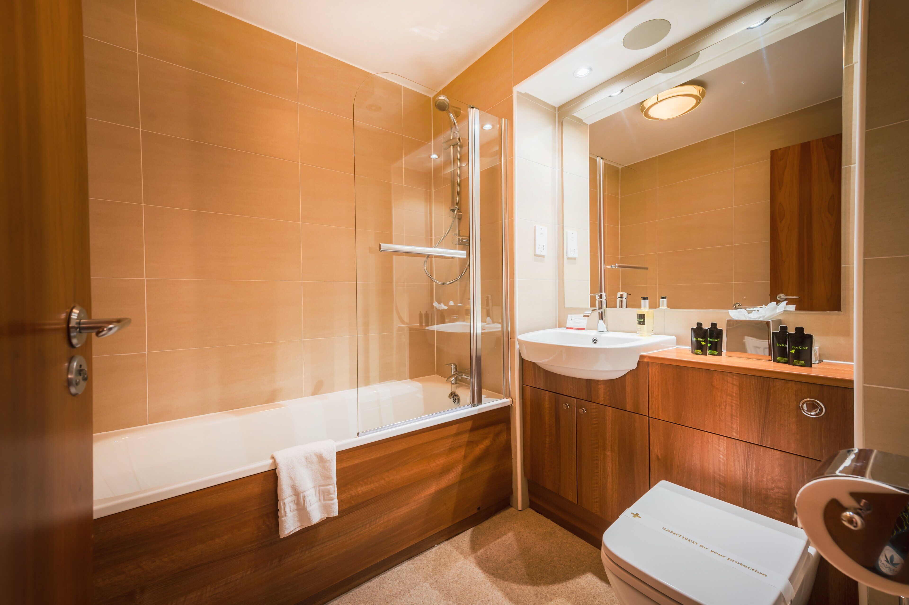 A modern bathroom with a glass-enclosed shower, a wooden vanity with a sink, and a toilet.