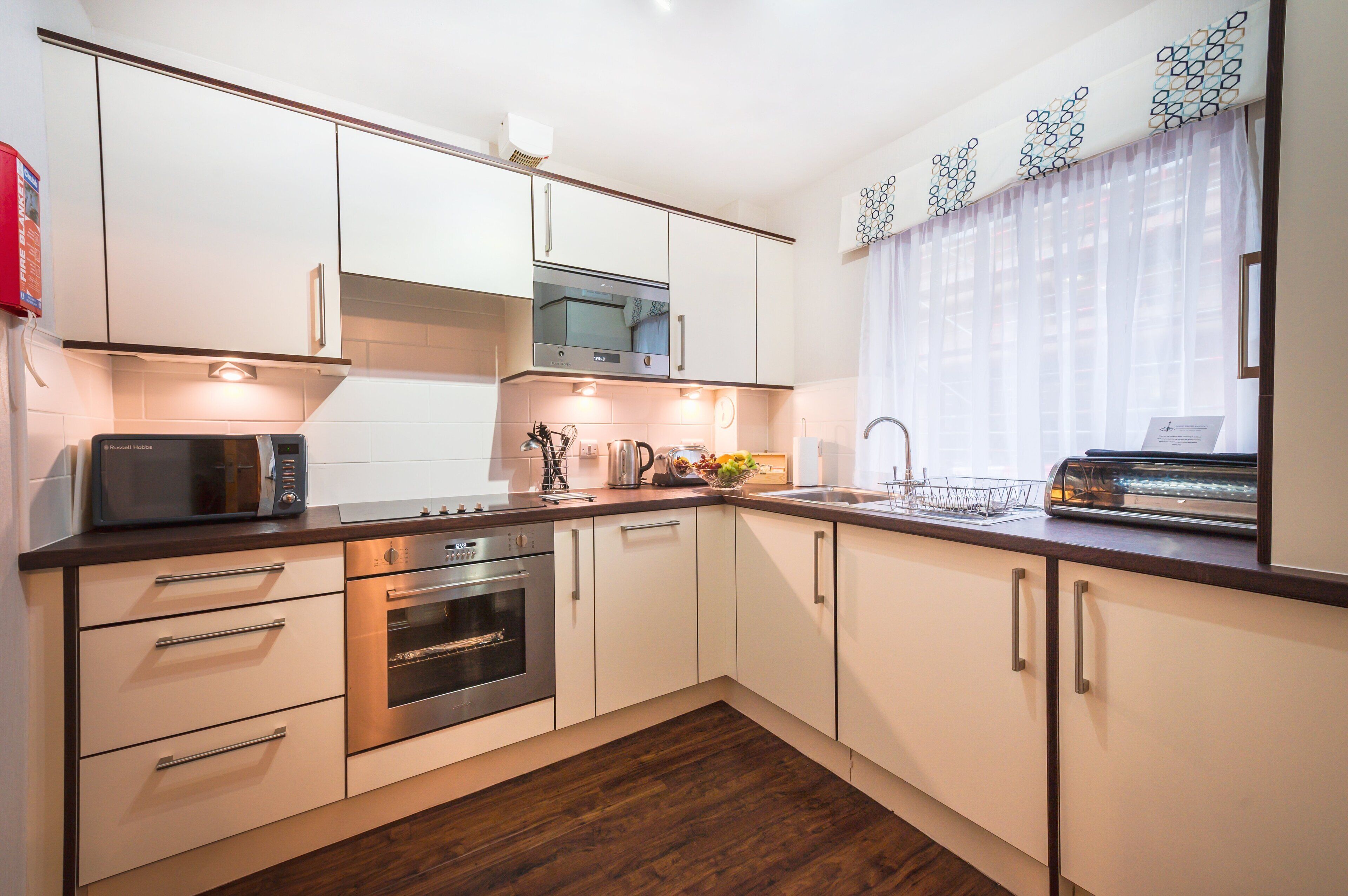 A modern kitchen with white cabinets, stainless steel appliances, and a wooden countertop.