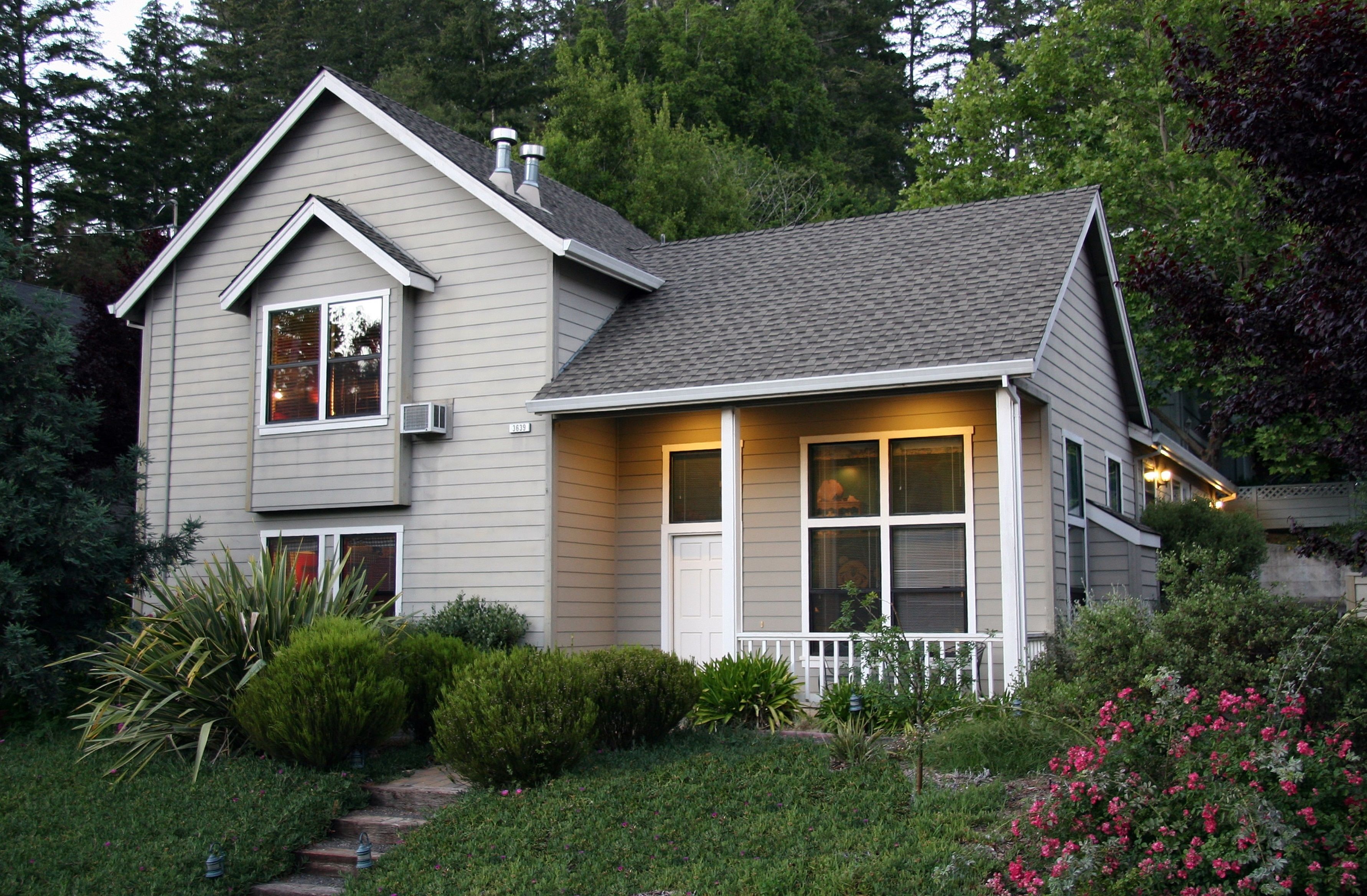 A two-story house with a front porch, a chimney, and a well-maintained garden.