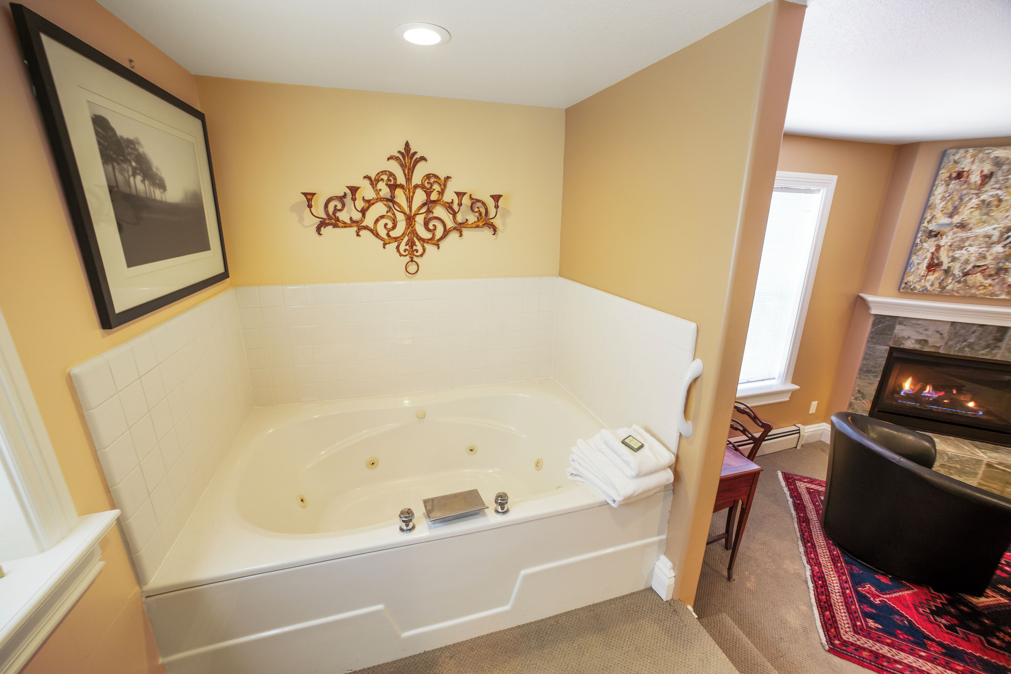 A room with a large bathtub, a fireplace, and a framed picture on the wall.