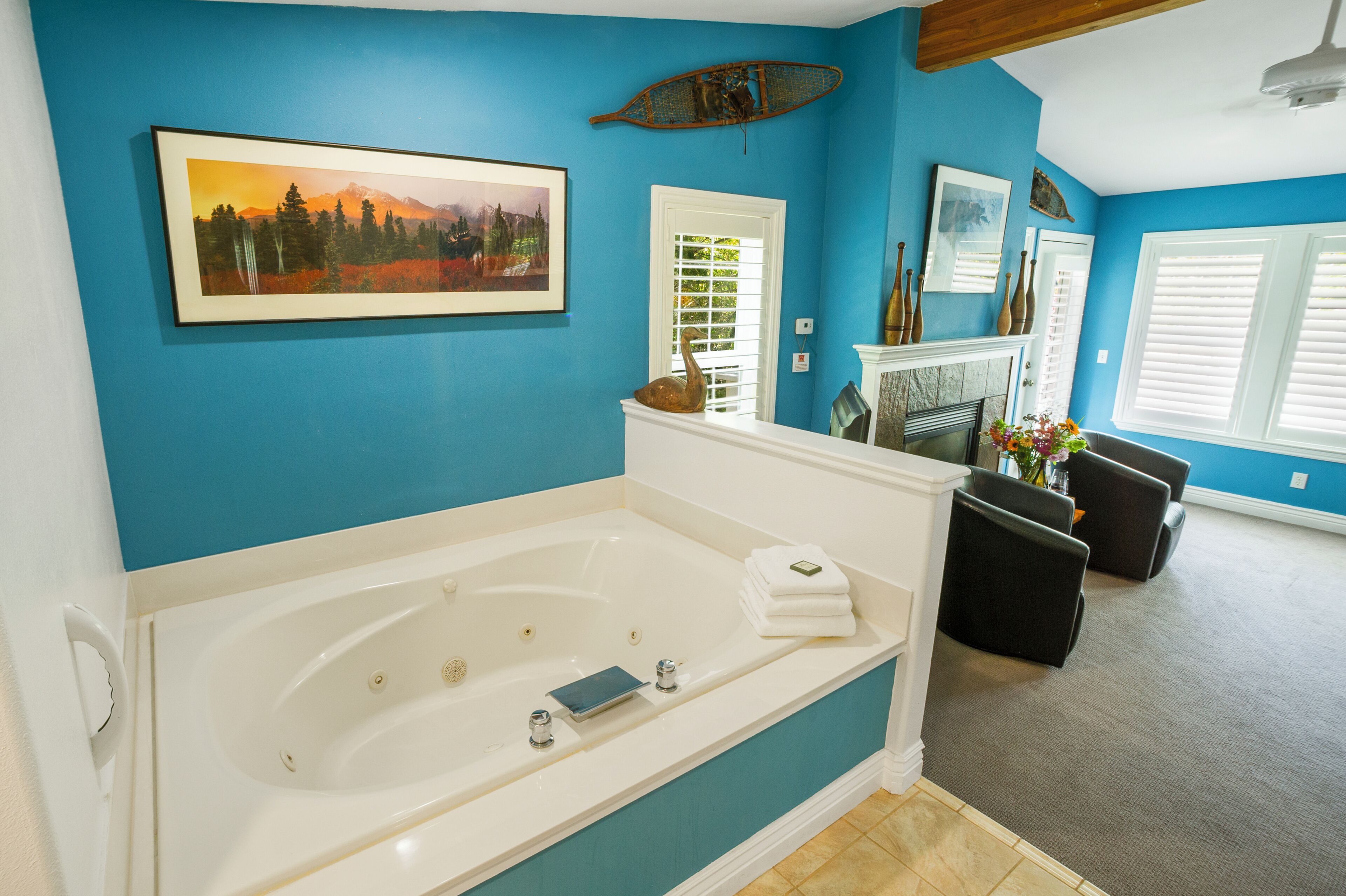 A bathroom with a large bathtub, a white door, and a blue wall.