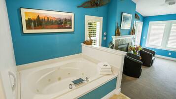A bathroom with a large bathtub, a white door, and a blue wall.