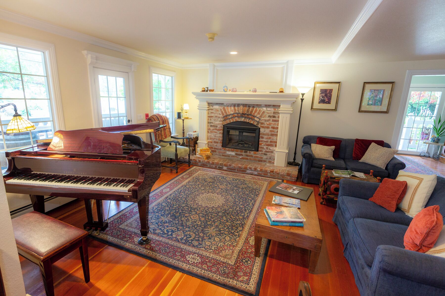 A living room with a grand piano, a fireplace, a sofa, and a coffee table.
