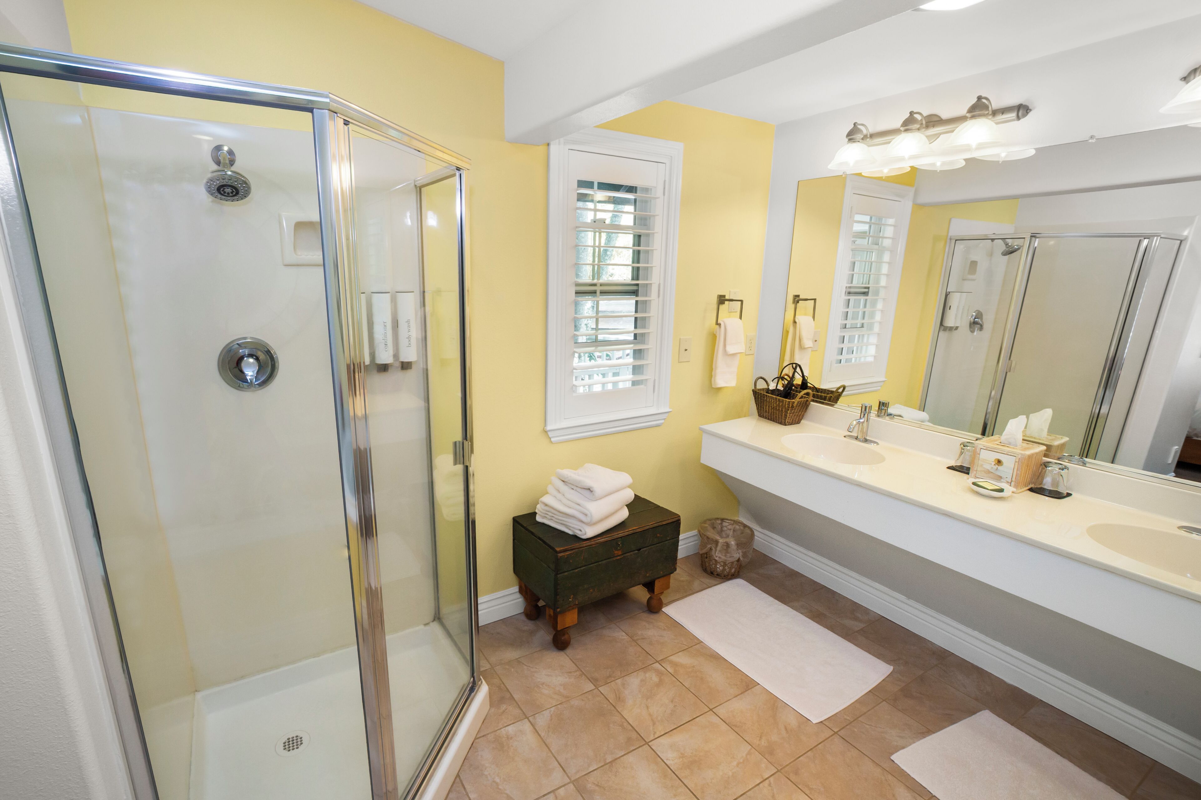 A bathroom with a glass shower enclosure, a vanity with a sink, and a large mirror.