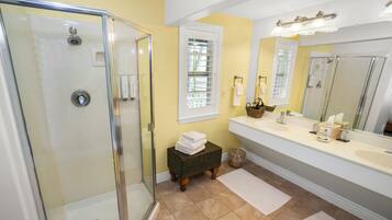 A bathroom with a glass shower enclosure, a vanity with a sink, and a large mirror.