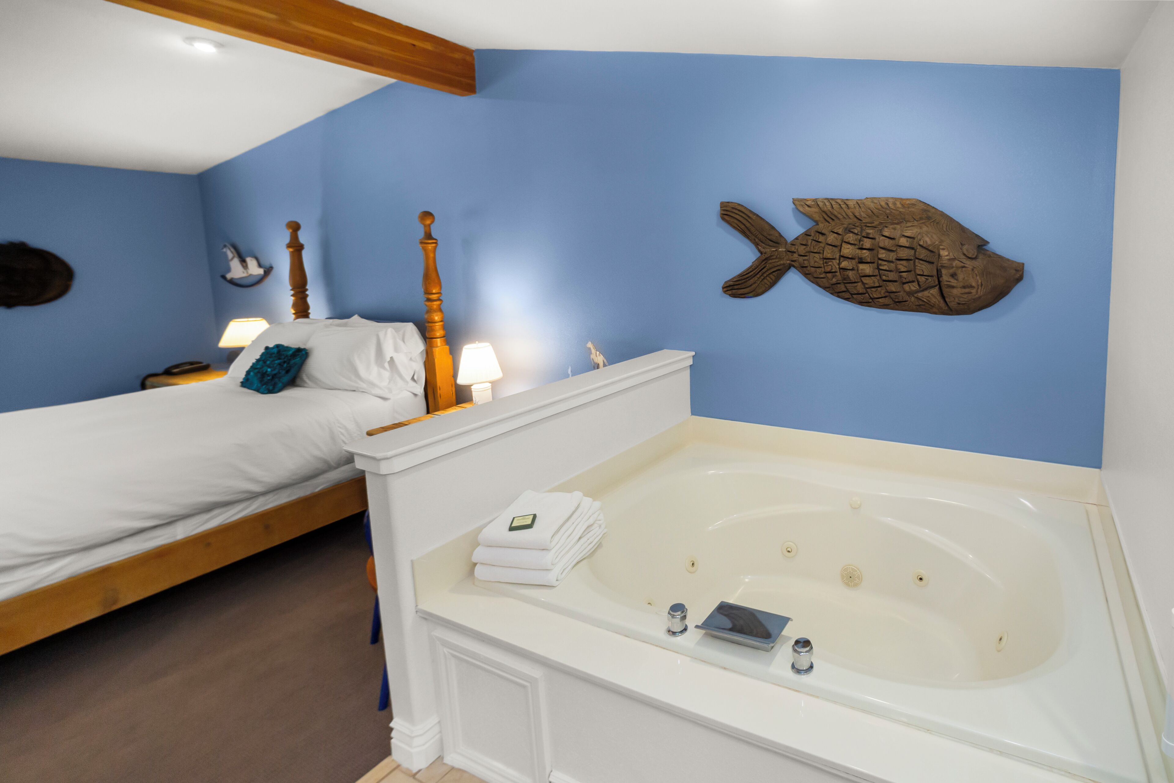 A bedroom with a bed, a large bathtub, and a wall-mounted fish decoration.