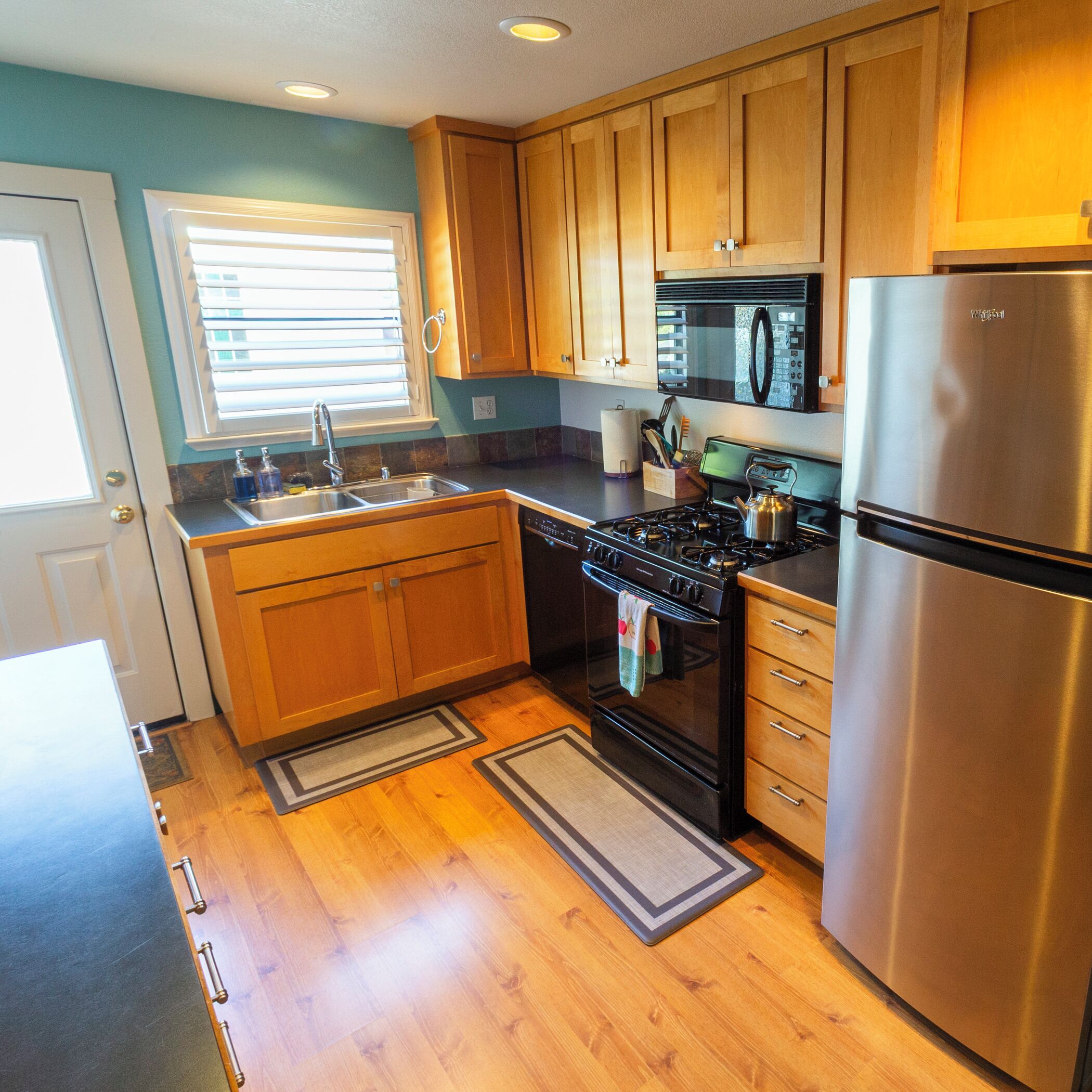 A kitchen with wooden cabinets, a stainless steel refrigerator, a microwave, and a stove.
