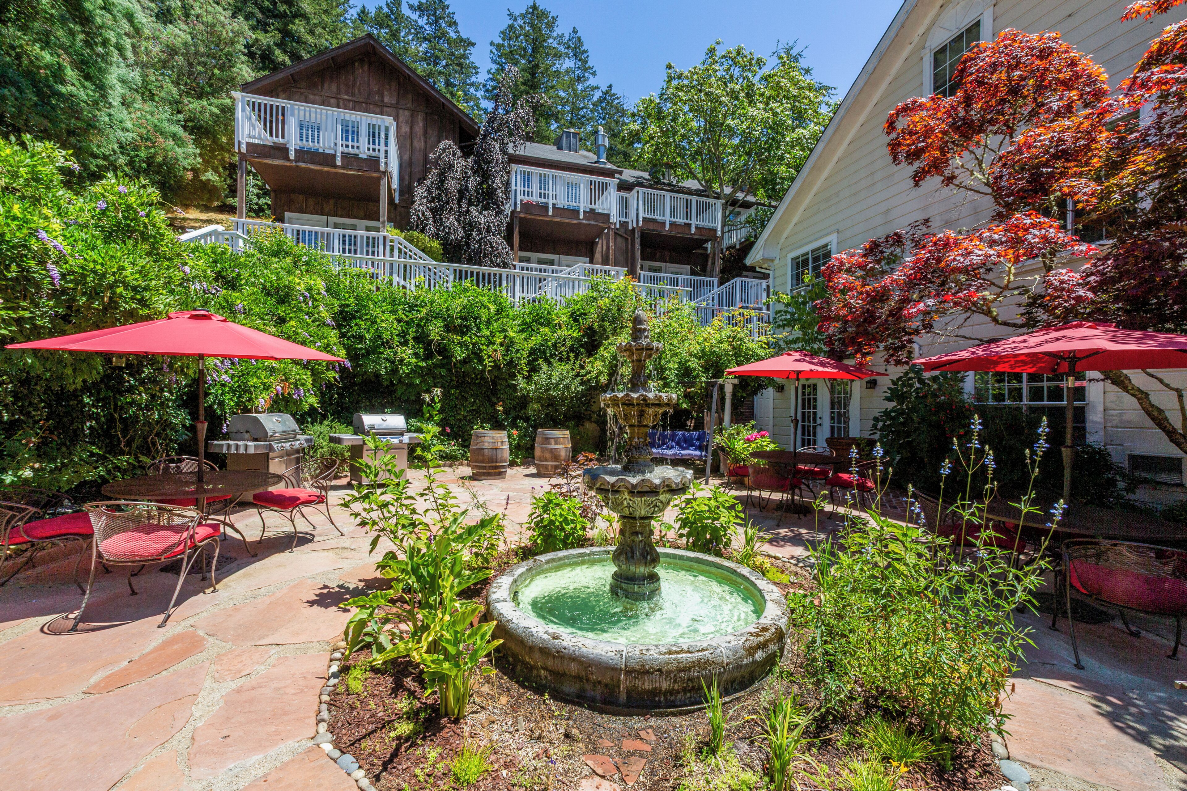 A courtyard with a fountain, outdoor seating, and a two-story building with balconies.
