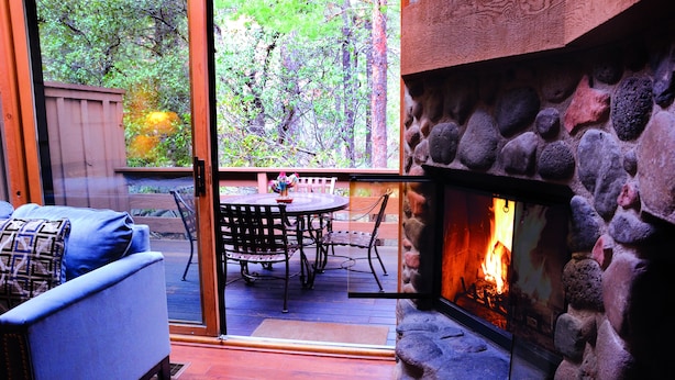 A cozy patio area with a stone fireplace, a blue sofa, and a dining table with chairs.