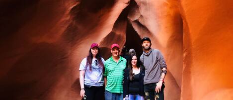 A group of people standing in a canyon with smooth, curved rock formations.