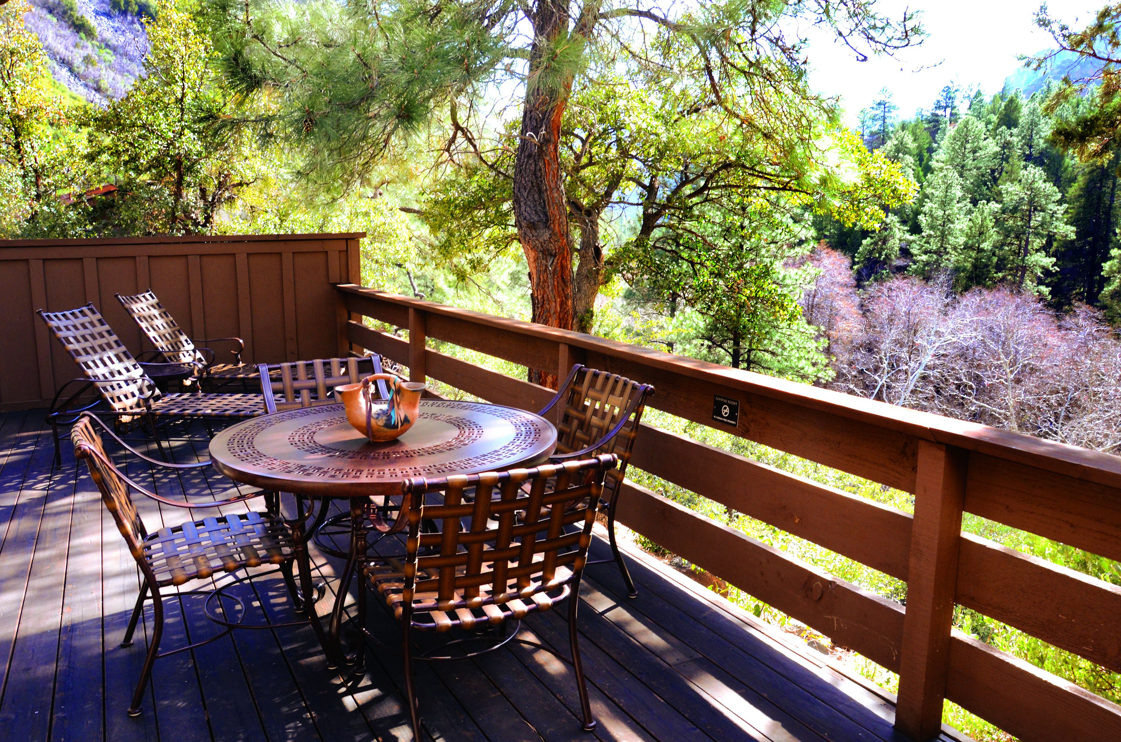 A wooden deck with a round table and chairs, surrounded by a wooden fence.