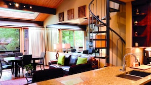 A modern kitchen with a granite countertop, a built-in sink, and a spiral staircase leading to an upper level.